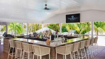 Un área de bar con una barra larga, varios taburetes y un letrero que dice "Margaritaville Beach House".