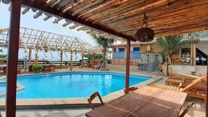 A pool area with wooden pergolas, lounge chairs, and a table. - Hotel Salinopolis e Kitepoint (Salinópolis)