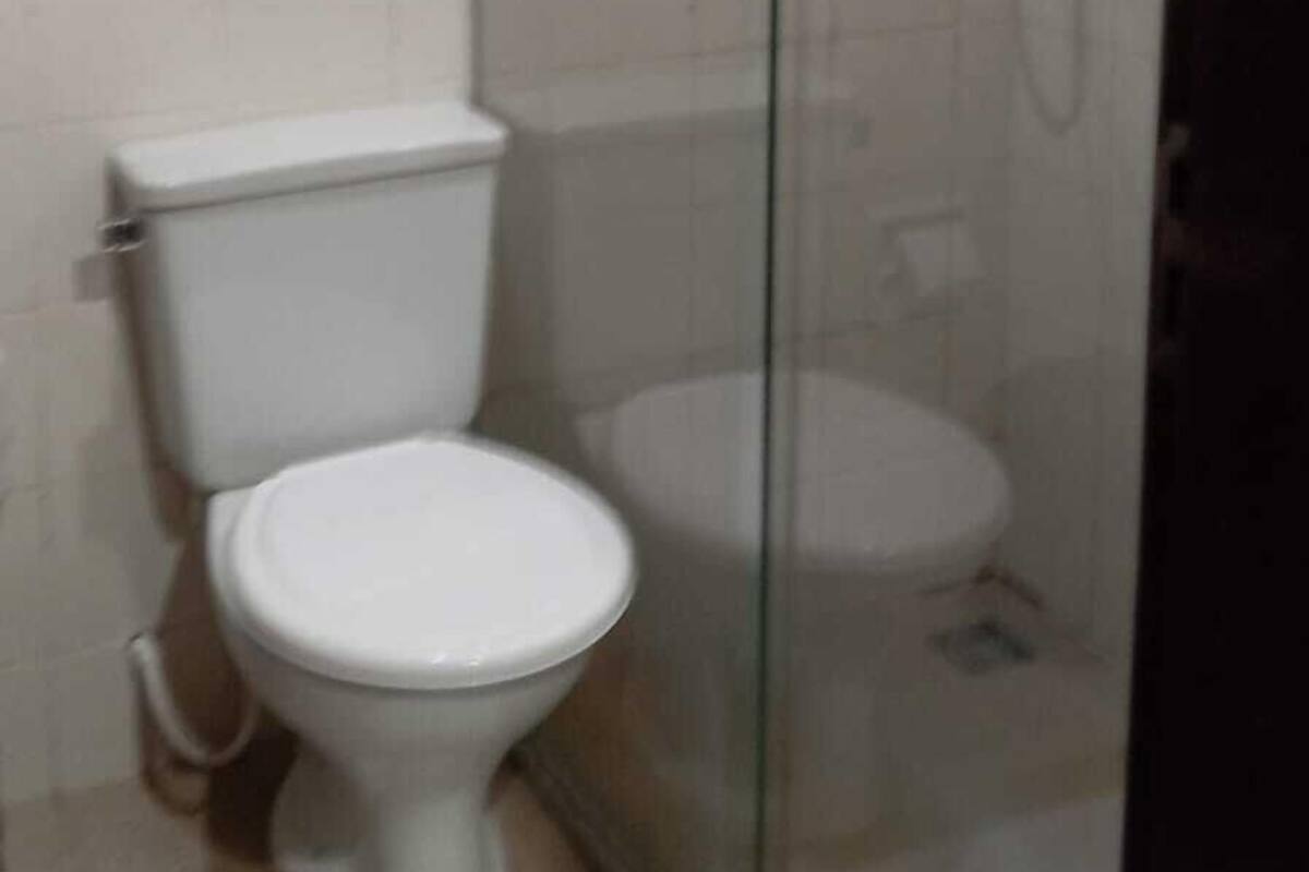 A bathroom with a toilet, a glass-enclosed shower, and a white tiled wall.