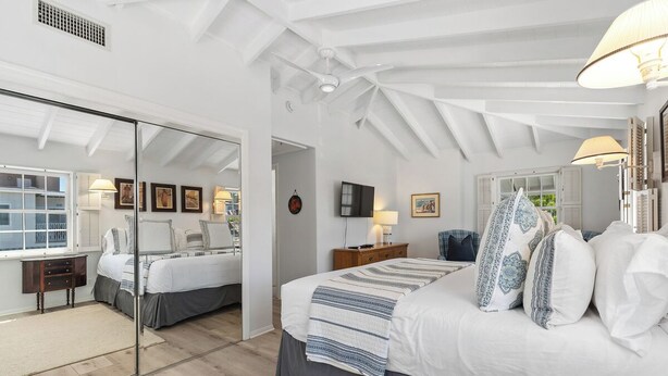 A bedroom with a large bed, a mirror, a TV, and a window.