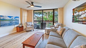 A spacious living room with a sofa, armchairs, a coffee table, and a ceiling fan. - Totally Renovated Maui paradise condo steps away from the beaches of South Kihei (Kihei)