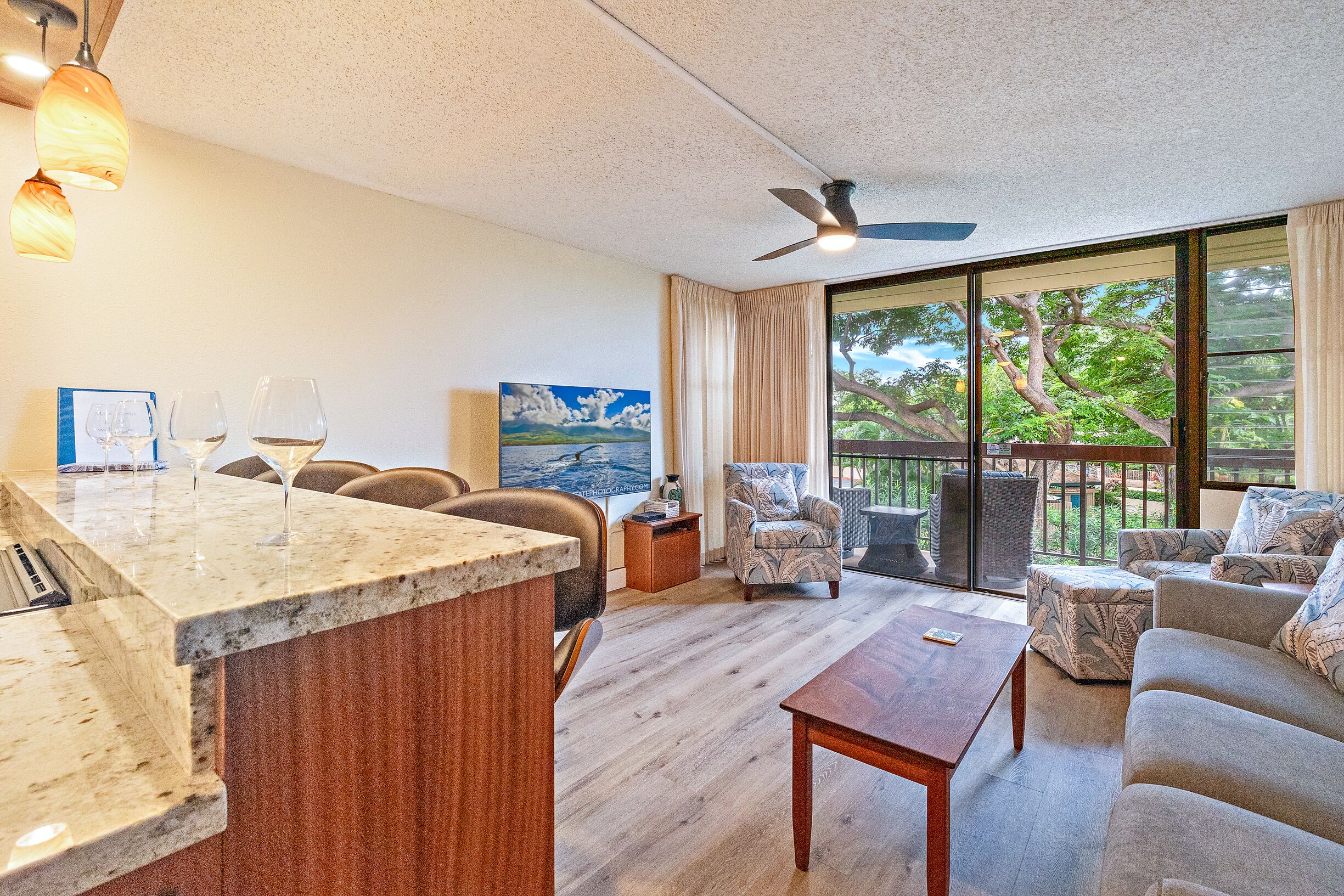 A spacious living area with a marble countertop, seating, and large windows offering a view of greenery.