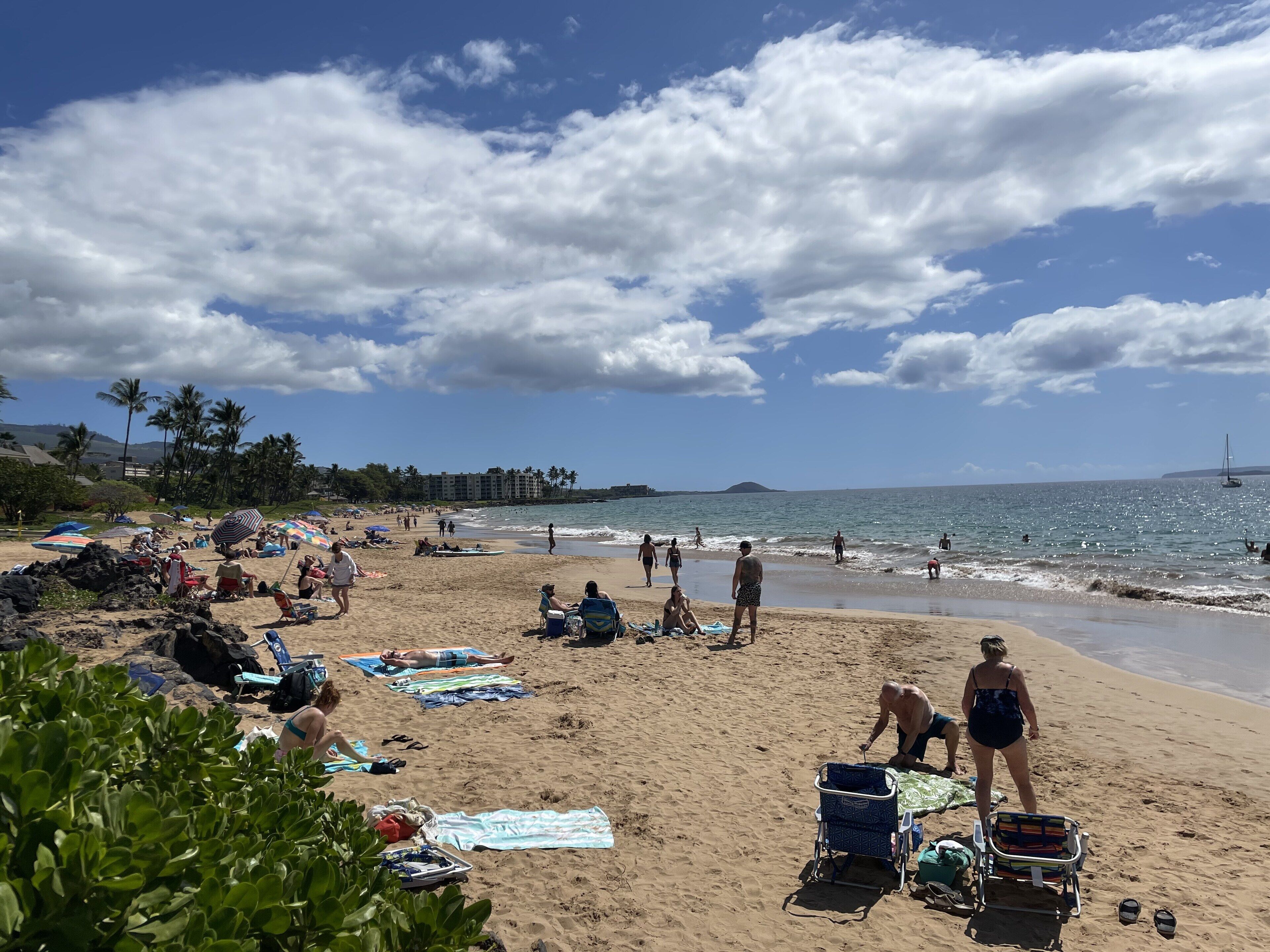 A beach with people sunbathing, umbrellas, and beach chairs.