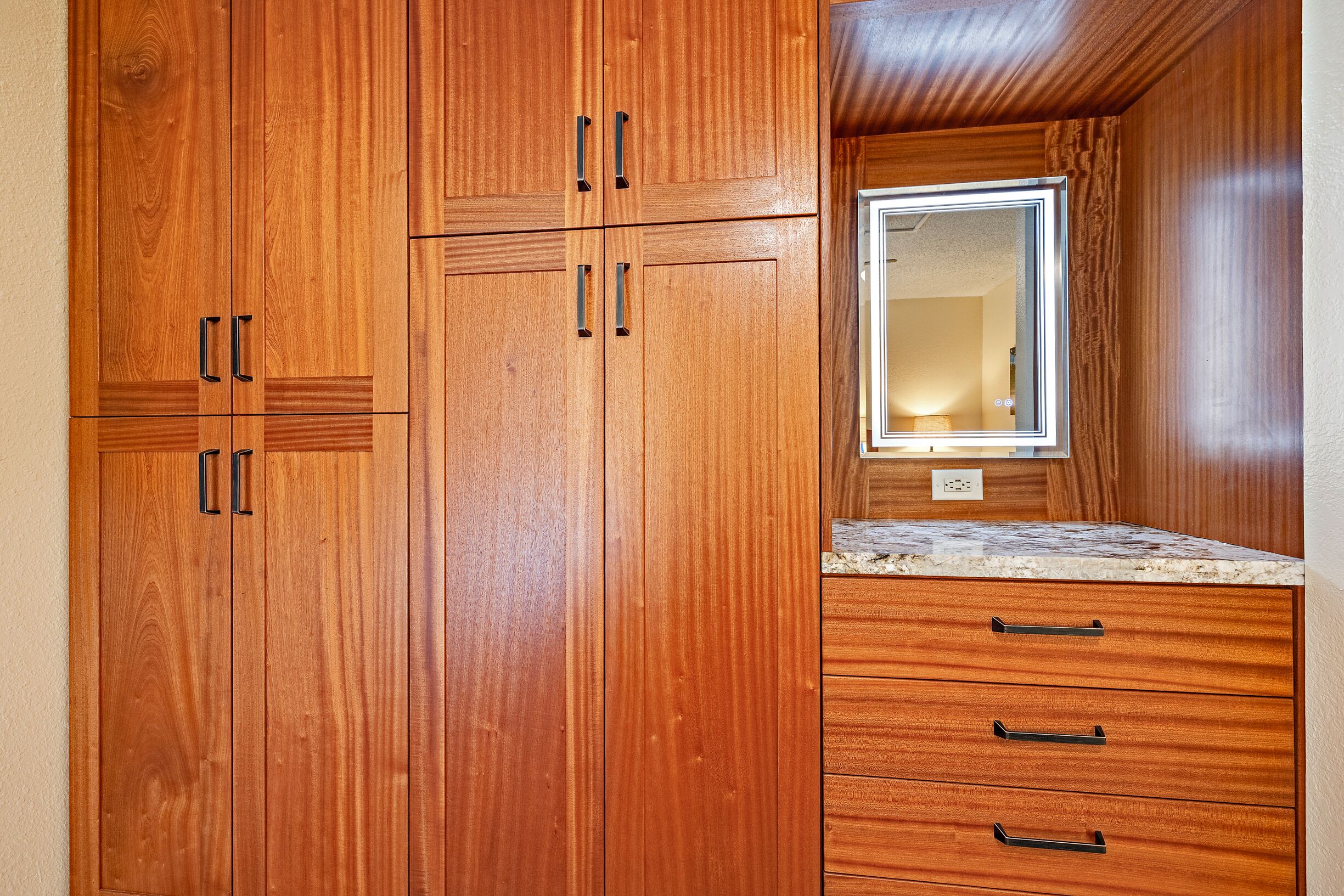 Une armoire en bois à deux portes, avec un miroir au-dessus d’un plan de travail.