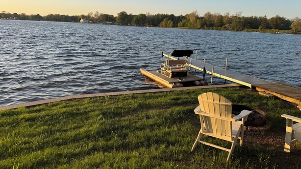 A dock extending into a calm lake with a grassy area and two Adirondack chairs. - Beautiful Skinner Cottage overlooking the lake (Albion)