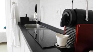 Et moderne køkken med en sort bordplade, kaffemaskine og vask.