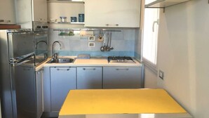 Ett kompakt kök med en gul köksbänk, vitvaror i rostfritt stål och vita skåp.