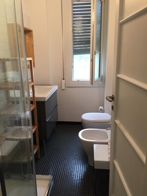 Et lille badeværelse med toilet, pissoir og et vindue.