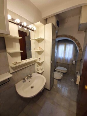 Une salle de bain moderne avec un grand miroir, un meuble-lavabo et deux toilettes.