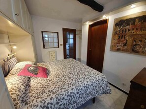 Une chambre à coucher avec un lit, une commode, une porte et un tableau au mur.