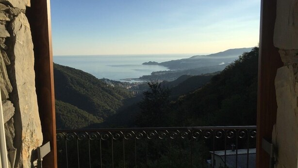 A balcony with a view of a coastal landscape, including hills, a body of water, and distant buildings. - Vista Portofino (Rapallo)