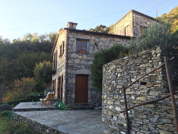 A stone house with a wooden door and a small balcony.