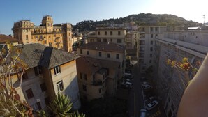 A cityscape with a mix of historic and modern buildings, a central street with parked cars, and a hill in the background.