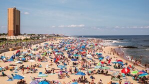 Een druk strand met veel parasols en mensen.