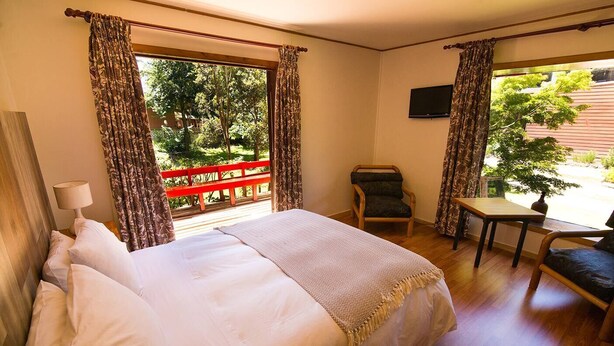 A hotel room with a bed, a chair, a table, and a TV. - Cabañas Terrazas del Lago (Puerto Varas)