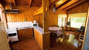 A wooden cabin interior with a kitchen, dining area, and a TV. - Cabañas Terrazas del Lago (Puerto Varas)