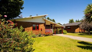 A two-story house with a covered porch and a well-maintained lawn. - Cabañas Terrazas del Lago (Puerto Varas)