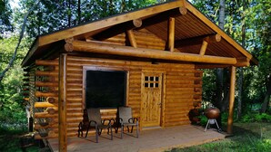 A log cabin with a porch, two chairs, a grill, and a large window. - Mont du Lac Resort (Superior)