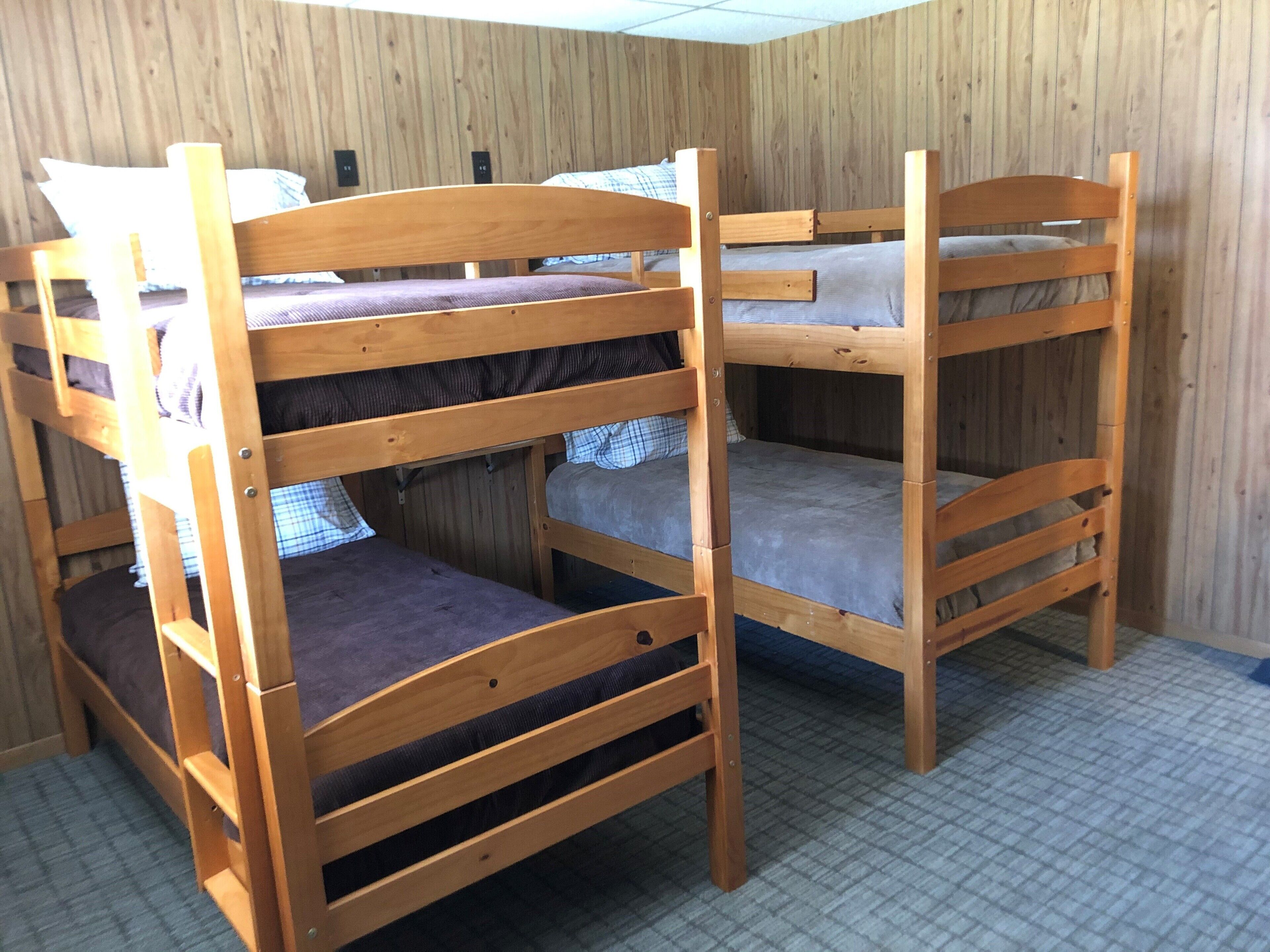 Ein Zimmer mit zwei Etagenbetten aus Holz, Holzwänden und einem Schachbrettfußboden.