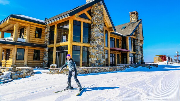 A log cabin with large windows and stone accents, surrounded by snow. - Mont du Lac Resort (Superior)