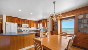 A kitchen with wooden cabinets, a central island, and a view of the ocean. - Waterfront property + Beach + Internet (Sturgeon Bay)