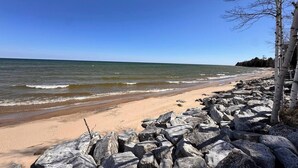 A rocky beach with waves, a clear sky, and birch trees. - Waterfront property + Beach + Internet (Sturgeon Bay)