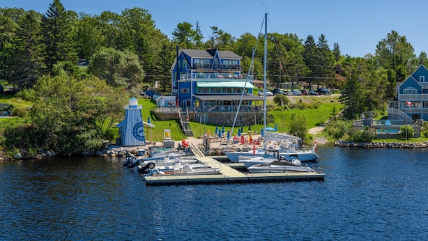 A waterfront property with a dock, boats, and a building with a balcony overlooking the water. - The Tuna Blue Inn and Restaurant (Hubbards)