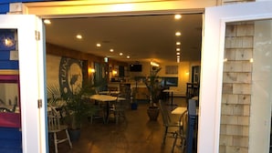 An interior view of a restaurant with a wooden floor, tables, chairs, and potted plants. - The Tuna Blue Inn and Restaurant (Hubbards)