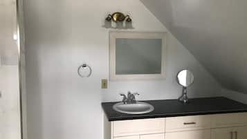 Un baño con tocador blanco, lavabo, espejo y argolla para toallas.