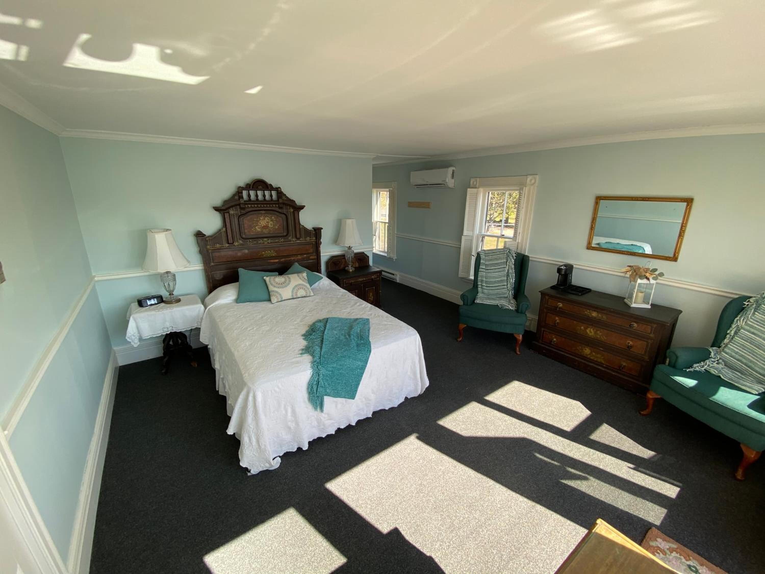 Een slaapkamer met een groot bed, een kaptafel, een stoel, een nachtkastje en een spiegel.