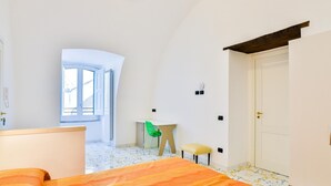 A bedroom with a bed, a window, a desk, a chair, and a wardrobe.