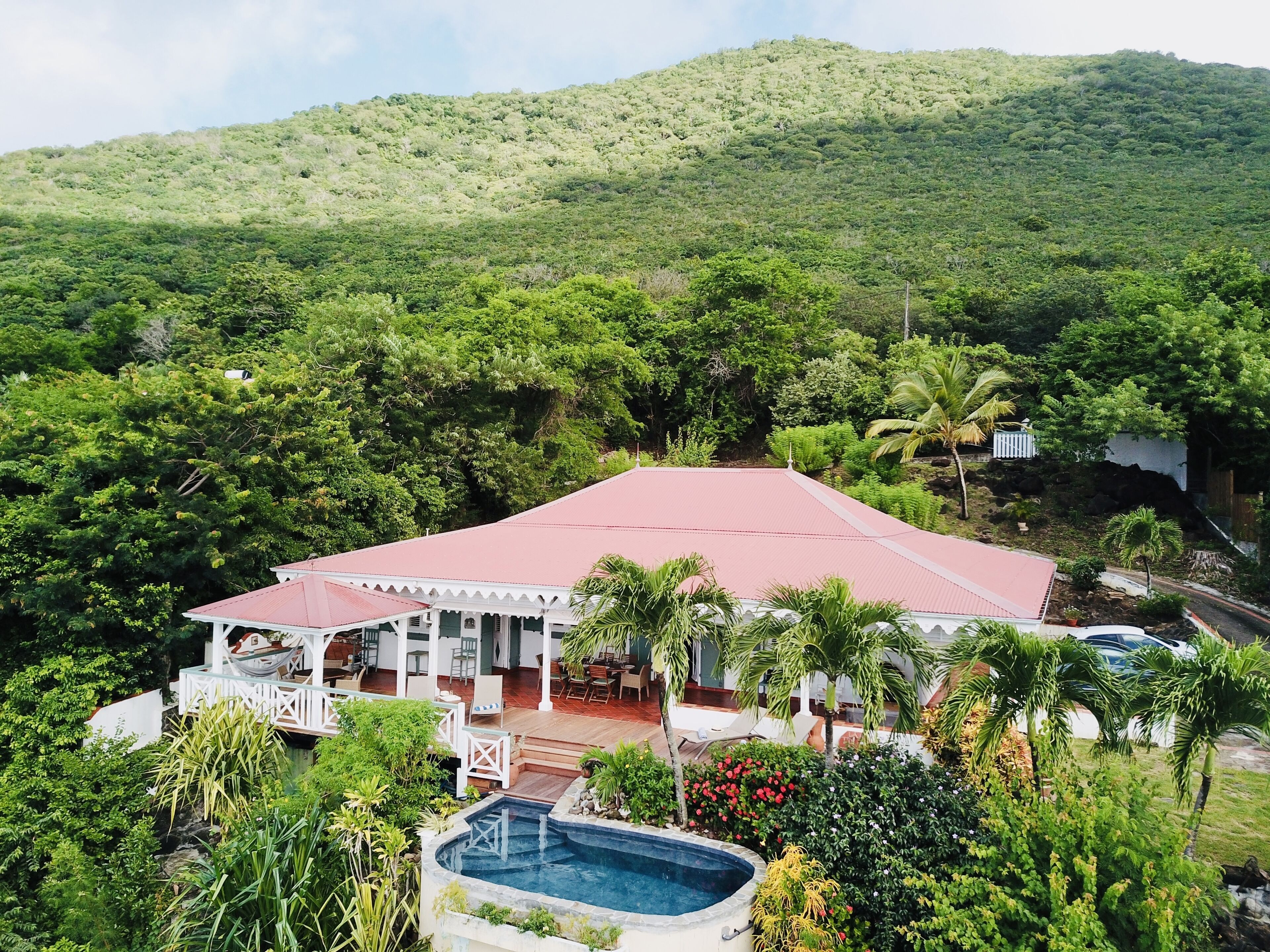 A resort with a swimming pool, outdoor seating, and a view of a lush green mountain.