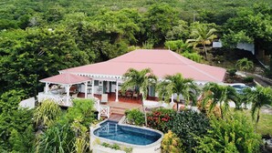 A resort with a swimming pool, outdoor seating, and a view of a lush green mountain. - Villa Cap Ouest - Private swimming pool and private sea access - Grande Anse (Les Anses-d'Arlet)