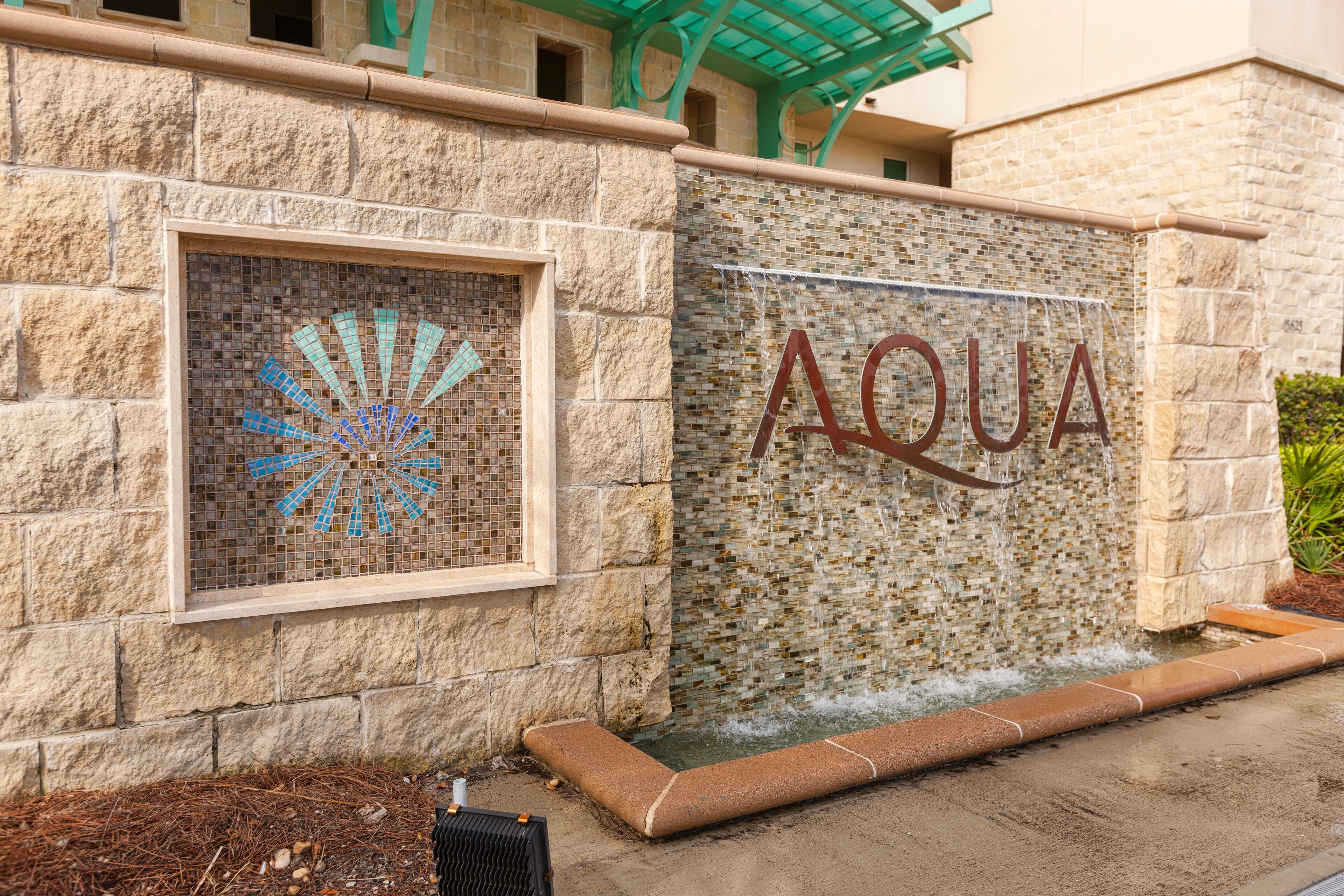 En stenvæg med et mosaikfanco og ordet "AQUA" i store bogstaver.