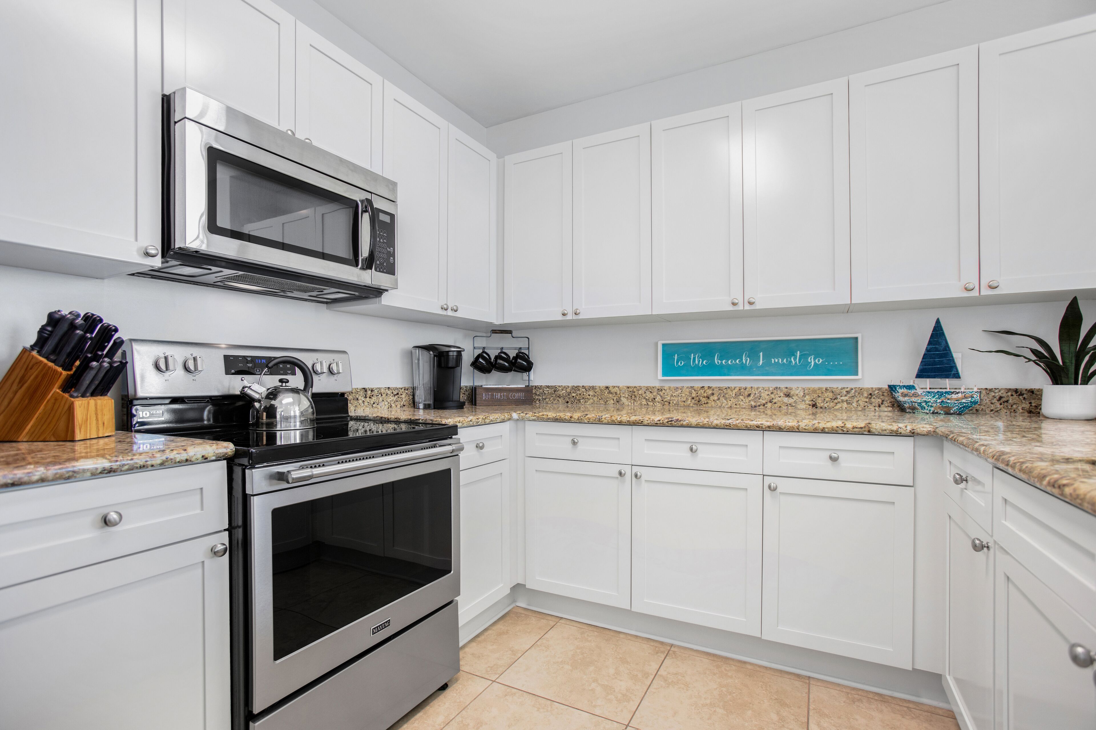 A modern kitchen with white cabinets, stainless steel appliances, and a granite countertop.