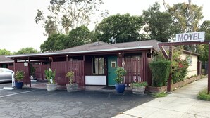 Un motel con fachada roja, puerta verde y un cartel que indica que es un motel.