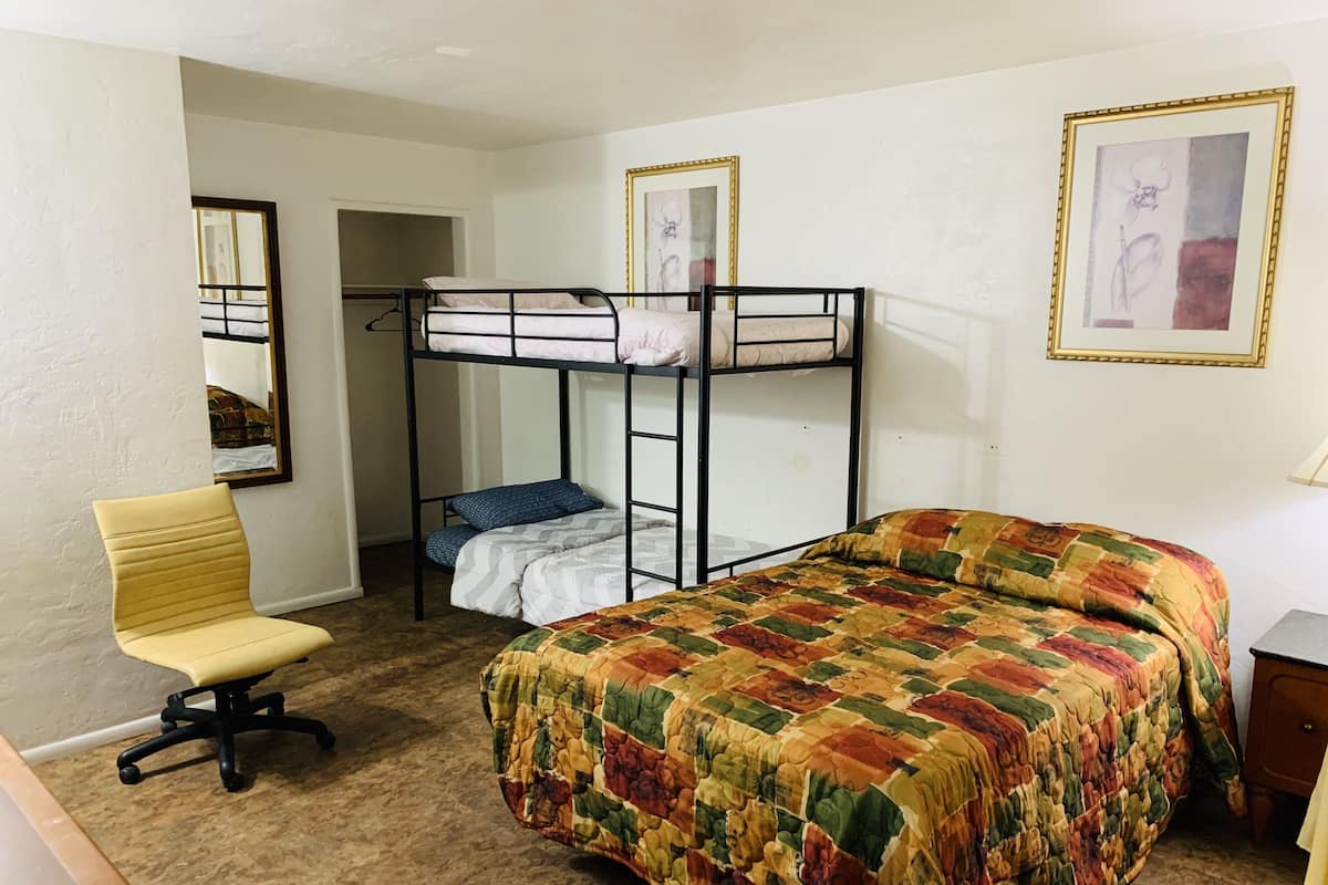 A room with bunk beds, a single bed, a chair, and a desk.