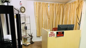 Una recepción con un ordenador, un reloj y un letrero que indica 'No se aceptan cheques'.