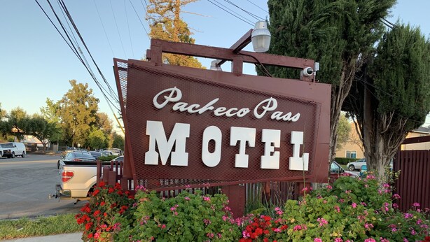Letrero del motel Packeco Pass con estructura metálica y letras blancas grandes.