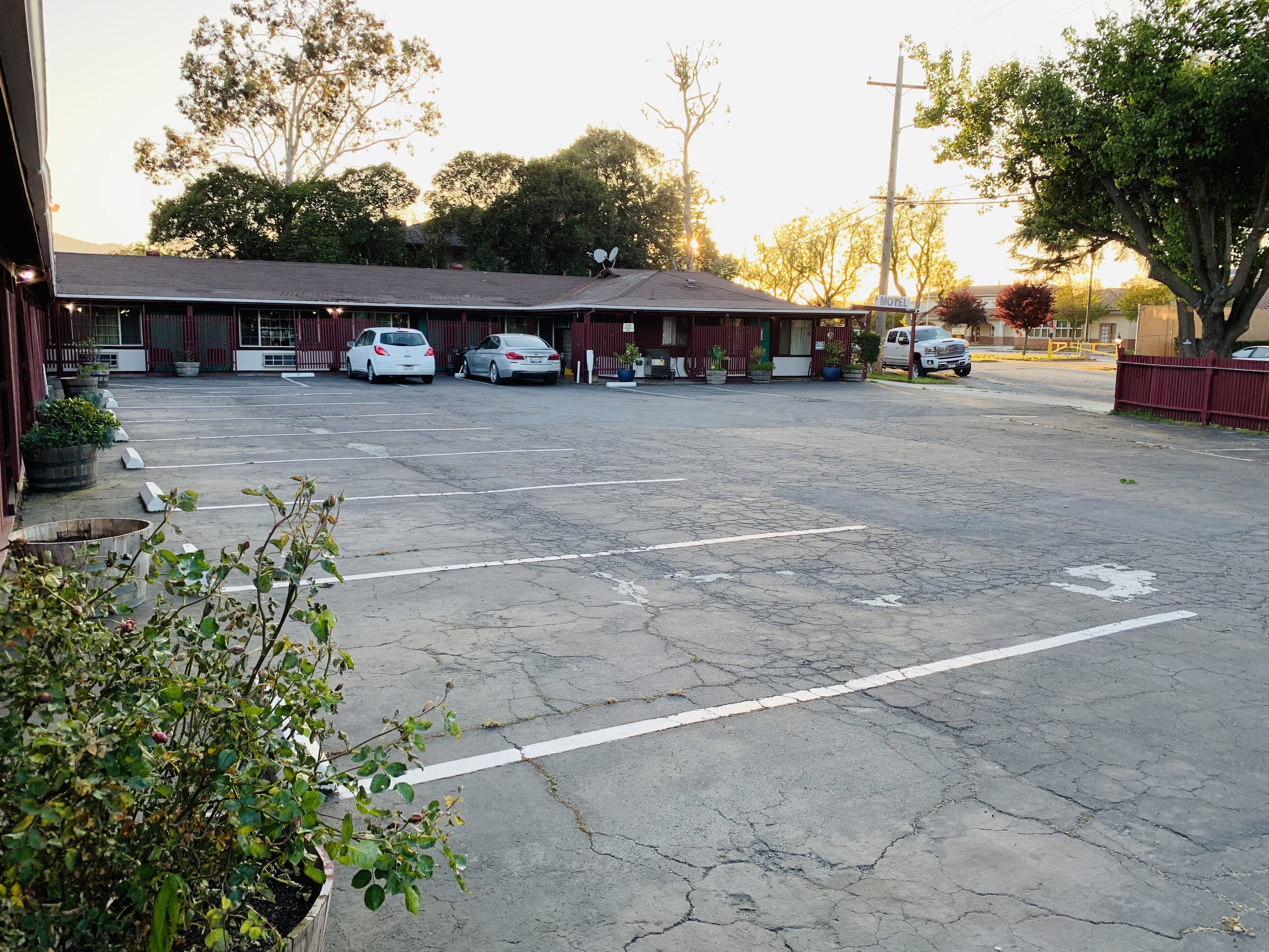 A motel with a parking lot, several cars parked, and a building with a red exterior.