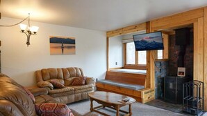 A cozy living room with a leather sofa, a wooden coffee table, and a fireplace. - JHRL - Aspens Juniper 114, perfect for a couple or single vacationers (Wilson)
