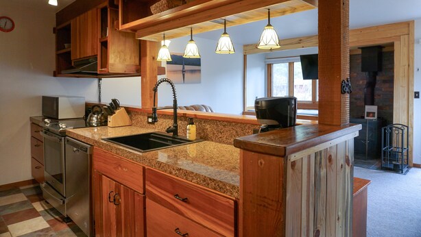 A kitchen with granite countertops, wooden cabinets, stainless steel appliances, and pendant lighting. - JHRL - Aspens Juniper 114, perfect for a couple or single vacationers (Wilson)