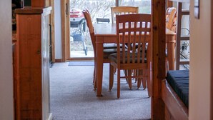 A wooden interior with a dining table and chairs, a bench, and a view through a glass door to the outside. - JHRL - Aspens Juniper 114, perfect for a couple or single vacationers (Wilson)