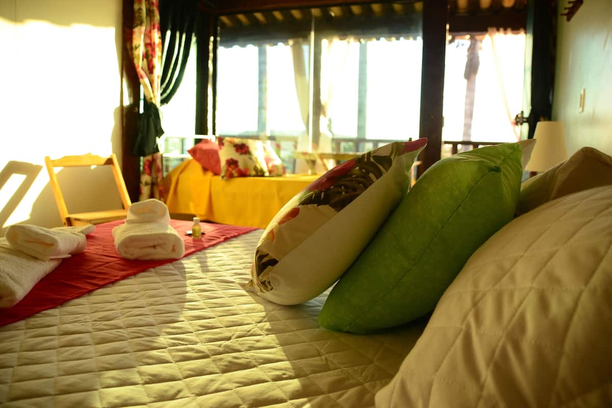 A bed with a quilted cover, pillows, and folded towels.