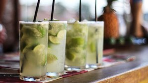 Tres vasos de una bebida a base de lima con pajitas, sobre una barra.