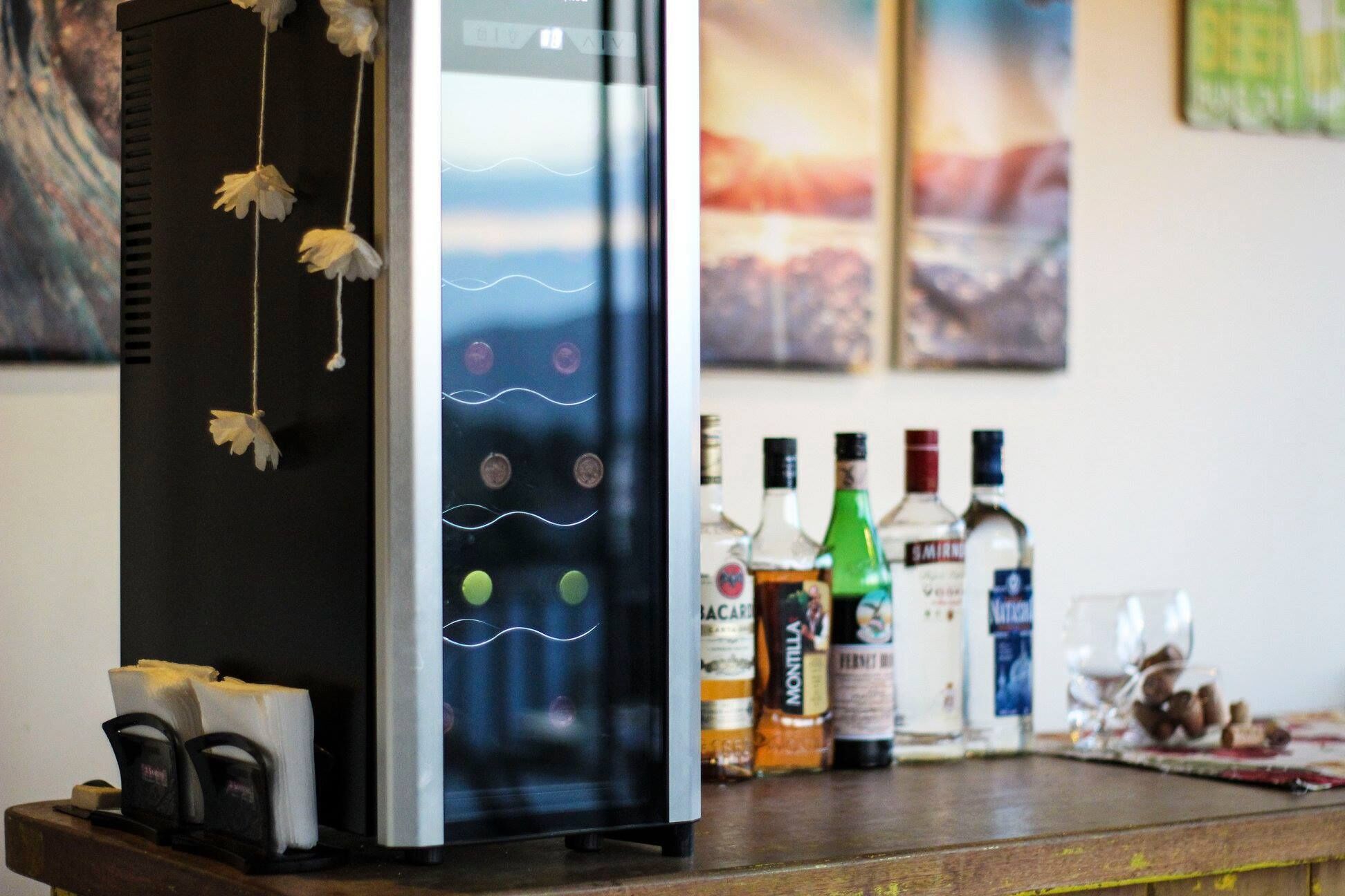 A bar area with a refrigerator, bar tools, and various liquor bottles.