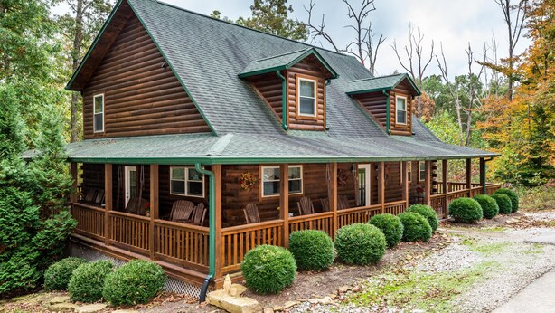 A log cabin with a porch, multiple windows, and a green roof. - 5BR, 5.5BA log cabin (Nashville)