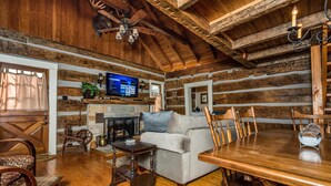 L’intérieur d’un chalet rustique, avec une table à manger en bois, un canapé et une cheminée.