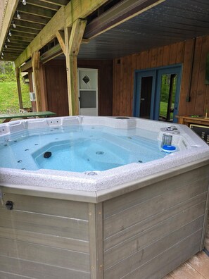 A hot tub with a wooden deck, a door, and a small table.