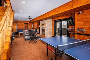 Un intérieur en bois avec une table de ping-pong, une cheminée et un mur en pierre.